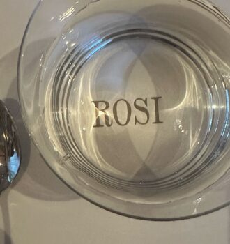 Leeres Glas mit ROSI-Logo auf weißer Tischdecke mit Besteck