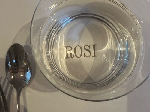 Leeres Glas mit ROSI-Logo auf weißer Tischdecke mit Besteck