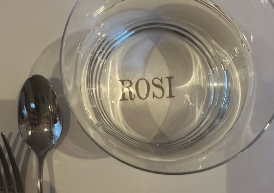 Leeres Glas mit ROSI-Logo auf weißer Tischdecke mit Besteck