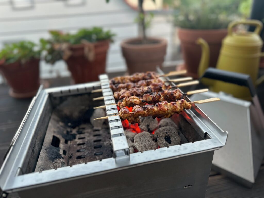Yakitori-Spieße auf dem Yakitori-Aufsatz über glühender Holzkohle im Thüros Minicater